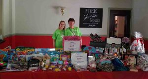 Two women standing next to a table with various items.
