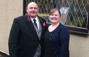 Clive and Lesley stand in front for window at Turners Funeral Service.