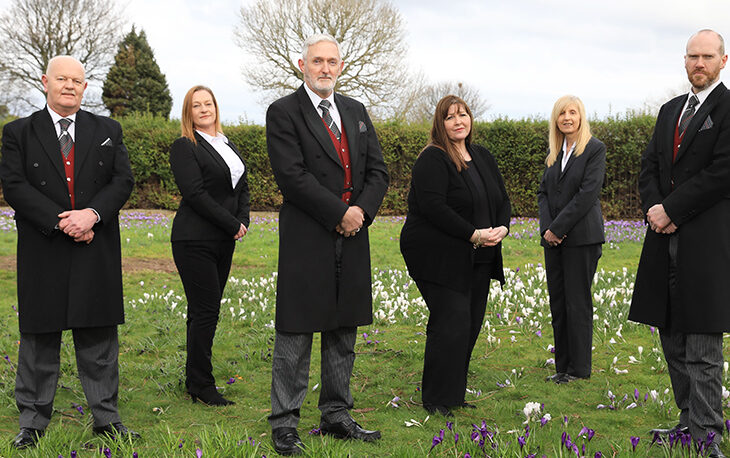 6 people in a line dressed in black and white suits.