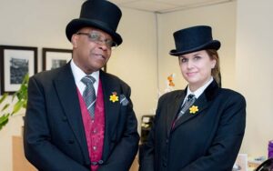Two people wearing black suits and top hats.