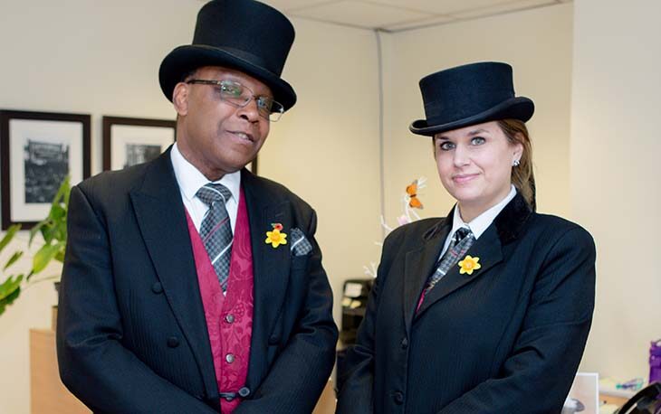 Two people wearing black suits and top hats.