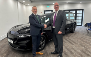Picture of two gentlemen, Graham and Sam shaking hands in front of a black electric hearse