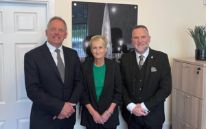 3 people standing together in front of a picture frame.