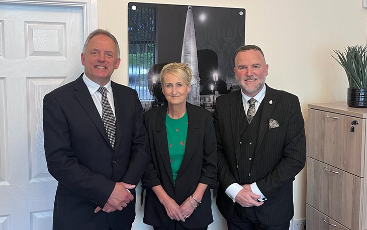 3 people standing together in front of a picture frame.