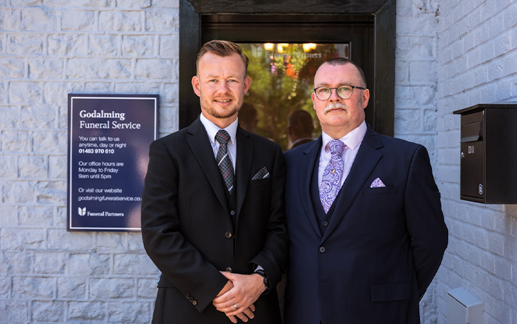 Two men in suits standing in front of the new Godalming Funeral Service.