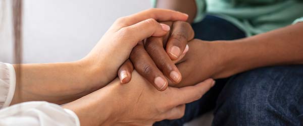 Woman comforting another by holding her hands
